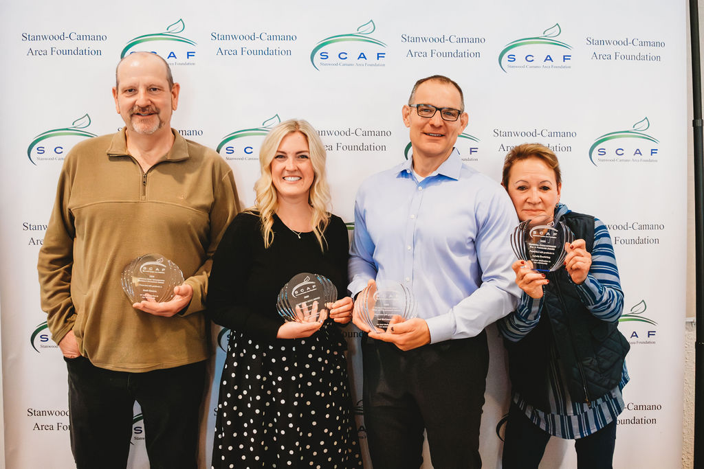 Les Swift, Taryn Daly, Ted McCammant, and Lynda Buehring are standing in a line holding their awards
